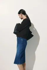 Pollera midi de jean azul, de cinco bolsillos, con tajo frontal y cierre con botón.