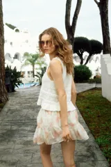 Musculosa corta de punto crochet color blanco, con escote redondo pronunciado con ribete festoneado y bajo acanalado de volado. Sin mangas.