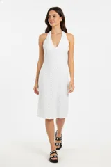 Vestido midi blanco con lunares negros, escote halter y corte ajustado.