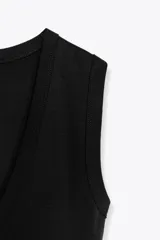 Camiseta negra de corte ajustado (slim fit) con escote pico pronunciado y manga sisa.