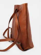 Mochila de cuero graneado color verde oscuro con detalles en cuero color marrón. Cuenta con un bolsillo exterior y un bolsillo interior con cierre, además de un compartimento interno para celular.
