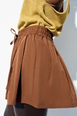 Bermuda color marrón con cintura elástica ajustable con cordones y bolsillos delanteros.