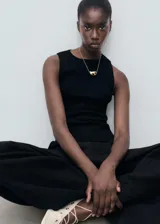 Musculosa negra de tejido de punto fino, con cuello redondo y tirantes anchos.