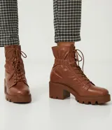Bota de cuero color marrón con cordones, caña media con detalle de elástico en la parte trasera, taco bloque medio y suela track.
