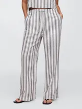 Pantalón largo de lino a rayas verticales blancas y azules, de corte palazzo con cintura alta y lazo ajustable.
