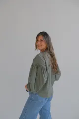 Camisa verde militar con bordado de flores, cuello mao con volados y mangas largas abullonadas con puños elásticos.