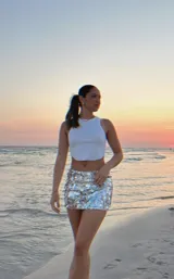 Minifalda plateada con lentejuelas espejadas, tiro bajo, elástico en la cintura y short interno.