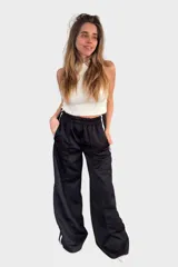 Pantalón negro de tela deportiva con cintura elástica ancha y cordón ajustable. Presenta corte amplio, bolsillos laterales y una franja blanca vertical a lo largo de cada pierna.