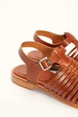 Sandalia de cuero color marrón con diseño de tiras entretejidas y hebilla lateral.