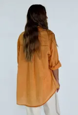 Camisa color naranja con cuello con detalle de puntilla, manga 3/4 y bolsillo en el pecho.