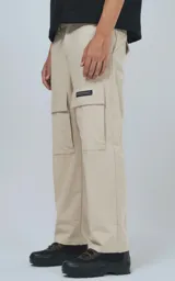 Pantalón cargo beige de corte recto con bolsillos laterales y etiqueta con logo en la pierna.