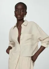Camisa color crema de bambula, con cuello camisero, manga larga con puños abotonados, bolsillo de parche en la parte delantera, diseño oversize y cierre delantero con botones.