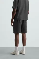 Bermuda negra de corte relaxed fit, con cintura elástica ajustable con cordón, bolsillos frontales y bolsillo trasero de parche.