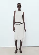 Camiseta sin mangas de encaje color blanco roto, con cuello redondo y tirantes anchos. Presenta un forro interior y un diseño recto.