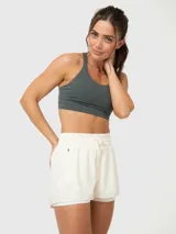 Top deportivo gris con breteles anchos cruzados en la espalda y costuras decorativas en el frente.