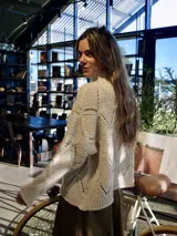 Sweater tejido color crema con cuello alto y motivo de rombos en el frente con hilos dorados.