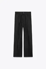 Pantalón negro de tiro medio con trabillas, pliegues frontales, bolsillos laterales y falsos bolsillos de vivo en la espalda. Cierre frontal con cremallera y botón.