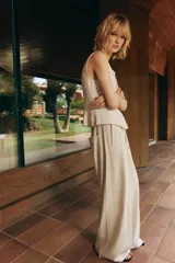 Pantalón ancho color verde oliva confeccionado en lino. Tiro alto con cintura elástica ajustable con cordón y pinzas delanteras. Presenta bolsillos laterales y traseros. Incluye cinturón de la misma tela con apliques metálicos.