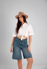Camisa blanca de manga corta con detalles de broderie y nudo para atar en la parte delantera.