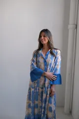Vestido largo celeste con estampado tie-dye en tonos beige, corte amplio y mangas 3/4 acampanadas.