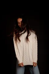 Sweater color crudo con cuello alto y diseño trenzado.