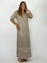 Vestido largo color beige, con escote en V y mangas cortas. Presenta un diseño batik en el ruedo.