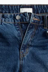 Pantalón de jean azul de corte acampanado, con tiro medio y cinco bolsillos.
