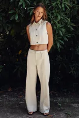 Pantalón de jean color crudo, de tiro alto y corte bootcut. Presenta cinturón fino del mismo tejido, bolsillos de parche en la parte trasera y cierre frontal con cremallera y botón.