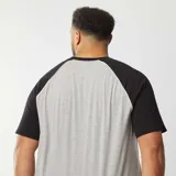 Remera gris con mangas cortas raglán negras y cuello redondo.