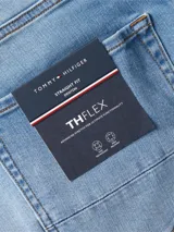 Pantalón de jean azul de corte recto, con cierre de botón y cremallera, cinco bolsillos y logo de Tommy Hilfiger en la parte trasera.