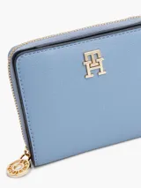 Billetera Tommy Hilfiger azul con cierre de cremallera y logo dorado en el frente. Confeccionada en poliuretano con acabado granulado.