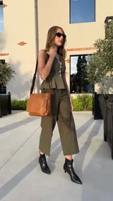 Bandolera de hombro color gris claro, con solapa frontal y correa ajustable. Presenta un diseño simple y práctico, ideal para uso diario.