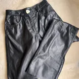 Pantalón de cuero negro, de corte recto y tiro alto, con bolsillos delanteros y traseros.