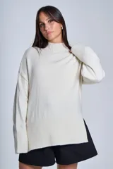 Sweater color crema de media polera, corte holgado y mangas largas. Tejido de punto con detalles acanalados en cuello, puños y ruedo.