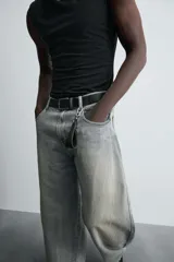 Pantalón de jean celeste con efecto lavado, corte holgado desde la cadera que se estrecha ligeramente en el bajo, tiro medio, cinco bolsillos y cierre frontal con cremallera y botón.