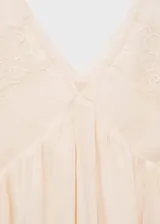 Vestido corto color crema con tirantes finos y escote en V, con detalles de encaje en escote y ruedo.