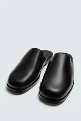 Zueco negro de cuero con punta redondeada y suela plana.