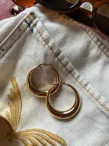 Aros tipo argolla gruesos, color dorado, hechos de titanio con baño de oro de 18k.