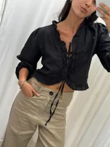 Blusa color blanco de lino, con mangas 3/4 y volados en el frente. Se ata con lazos en el centro.