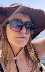 Lentes de sol de mujer con armazón grueso de policarbonato color rosa translúcido y lentes oscuros degradados. Diseño de montura geométrica con puente doble.