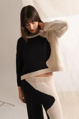 Sweater tejido color crema con mangas ranglán color beige y cuello redondo.