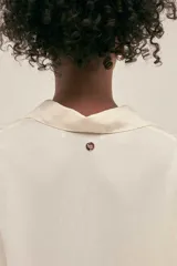 Camisola corta color crema confeccionada en lino-tencel con botones nacarados y bolsillos laterales.