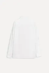 Camisa blanca de popelina de algodón con corte recto, cuello solapa, manga larga con puños abotonados, cierre frontal con botones y detalle de panel central en tejido de contraste.