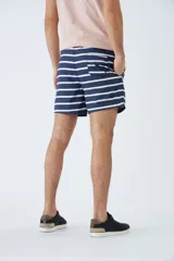 Short de baño azul con estampado de hojas y flores en blanco. Tiene cintura elástica con cordón ajustable, dos bolsillos laterales y uno trasero.