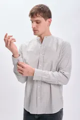 Camisa de manga larga con cuello mao y cierre frontal con botones. Diseño a rayas verticales en tonos blanco y marrón.