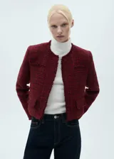 Chaqueta corta de tweed color rojo con terminaciones deshilachadas, cuello redondo, cierre frontal con botones y dos bolsillos de ribete delanteros.