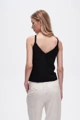 Musculosa blanca de bretel ancho con cuello en V y detalle de ojales metálicos en los tirantes. Corte al cuerpo.