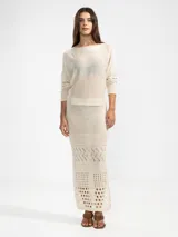 Falda larga color crema, tejida con diseño calado y corte en la parte trasera.