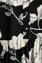Vestido corto de viscosa con estampado floral en blanco y negro. Modelo de corte holgado con cuello mao, botones delanteros y mangas globo largas con abertura y botón en los puños. Costura fruncida en la pollera para un efecto evasé.
