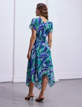 Vestido midi de gasa estampada con motivos florales en tonos azules y verdes. Escote en V tanto en la parte delantera como en la espalda. Corte en la cintura con punto smock y ruedo asimétrico.
